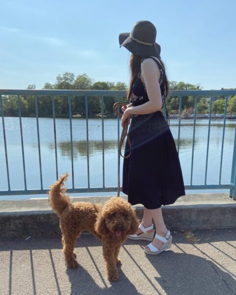 Une femme et son caniche se promènent autour d'un lac. La femme est minimaliste en devenir et entrepreneuse.