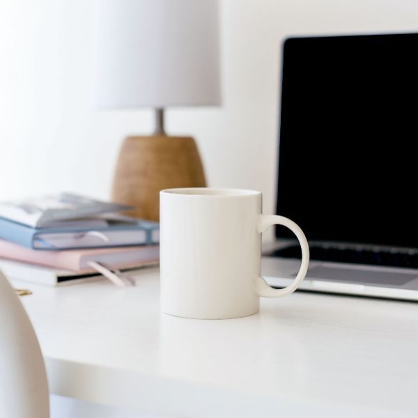 Une tasse blanche sur un bureau d'un entrepreneur ayant adopté le slow business. Pratiquer le slow entrepreneuriat pour faire plus avec mois.