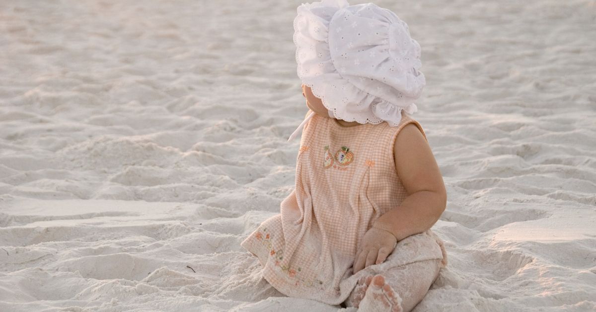 Une petite fille sur la plage. Ce bébé porte un prénom court pour fille, choisi par ses parents minimalistes